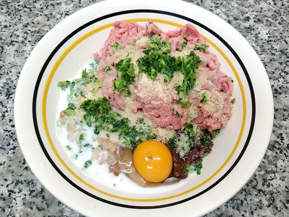 Cuenco con carne picada, gambas picadas, butifarra negra, huevo, leche, pan rallado ajo y perejil.