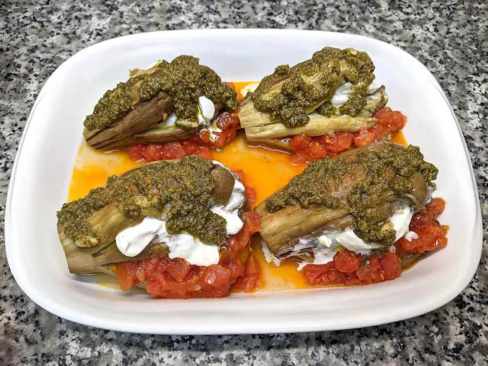 Berenjena horneada rellena con sofrito de tomate, burrata y pesto.