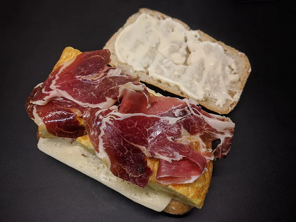 Chapata con havarti, tortilla de patatas, jamón ibérico y mayonesa.