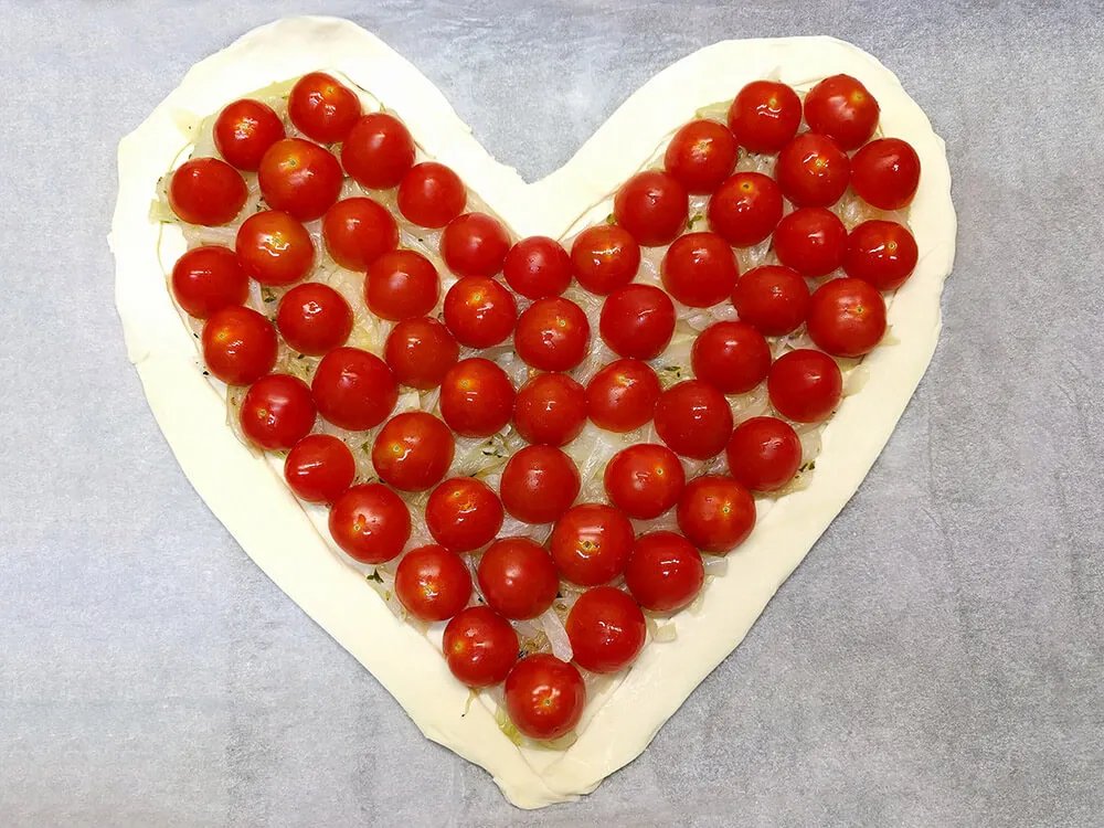 Corazón de hojaldre con cebolla frita y tomates cherry