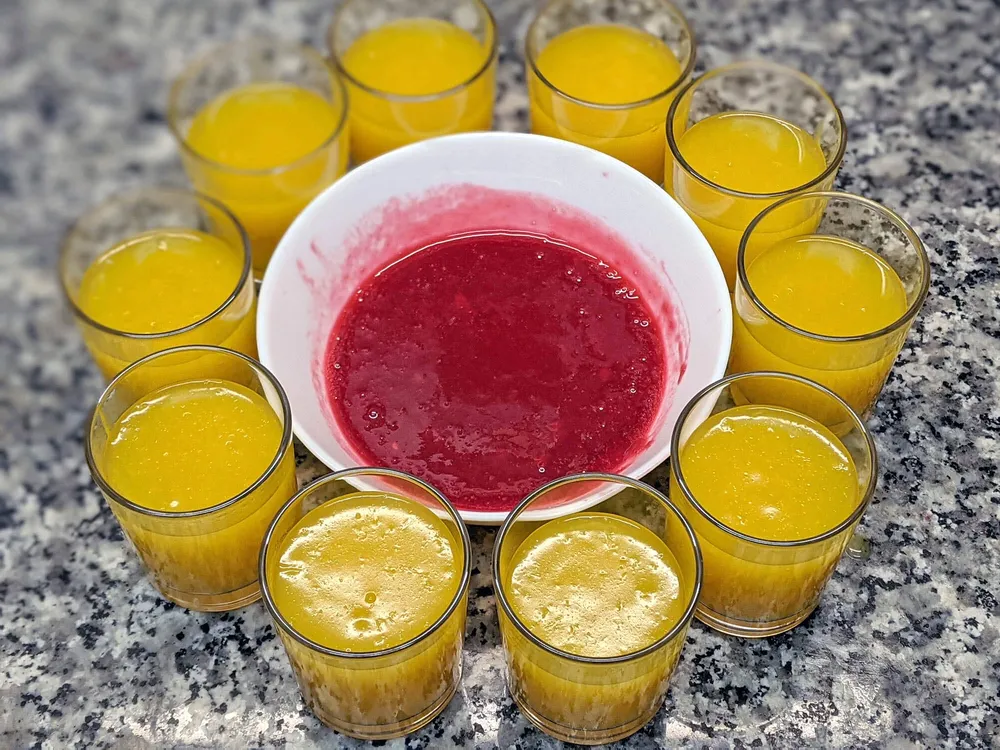 Crema de naranjas en vasos y coulis de frambuesas.