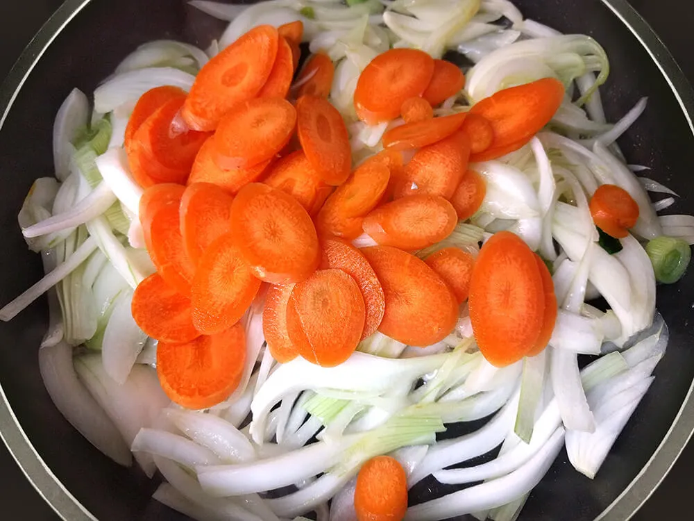 Cebolla en juliana y zanahoria a rodajas rehogándose