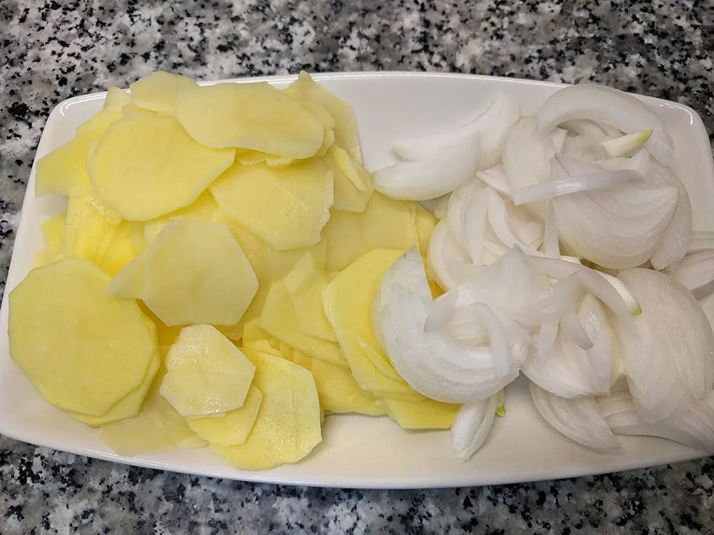 Patatas cortadas a rodajas finas y cebolla en juliana