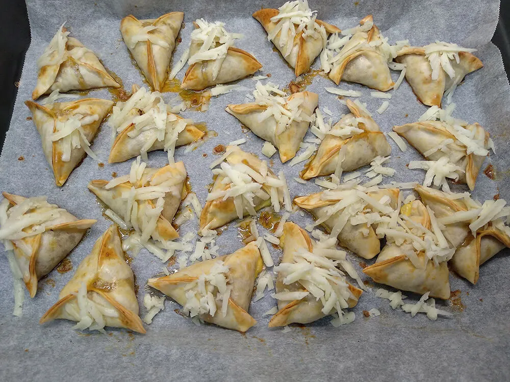 Empanadillas de ternera listas para gratinar con queso rallado.