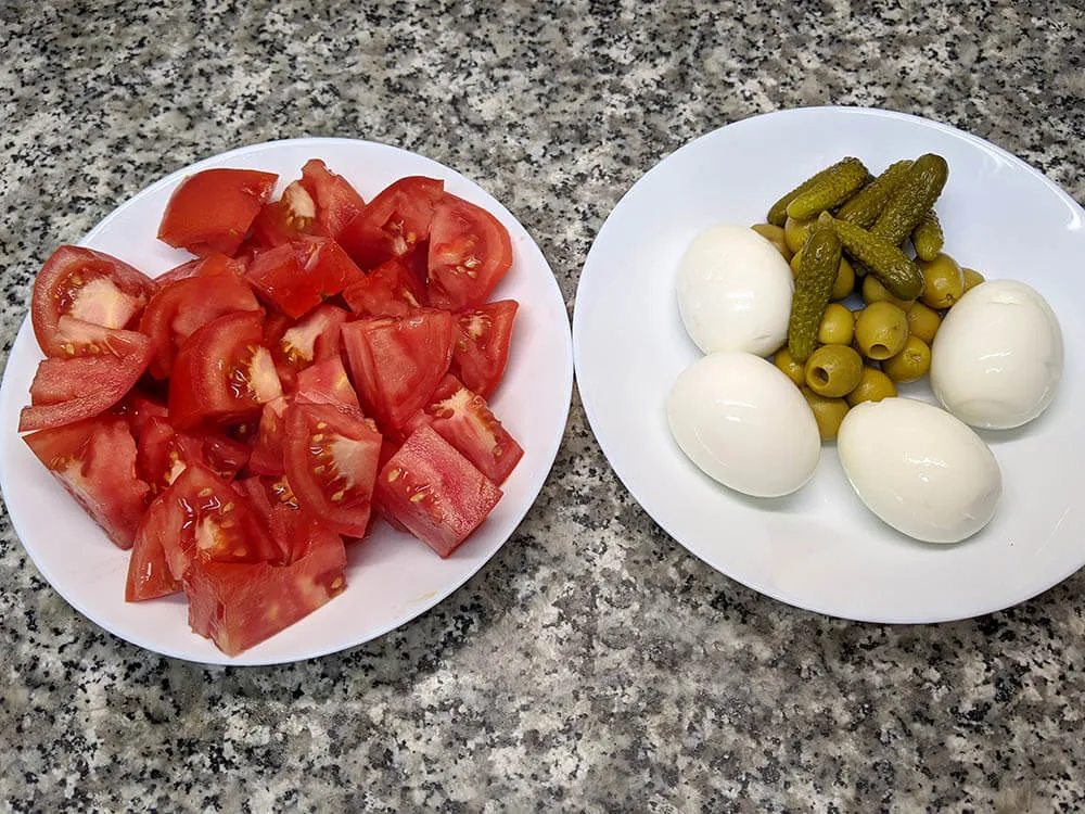 Tomate a dados, huevos cocidos, olivas y pepinillos.