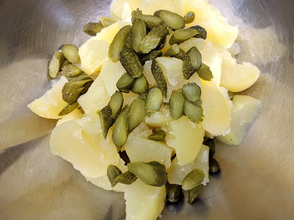 Patatas cocidas cortadas y pepinillos cortados.