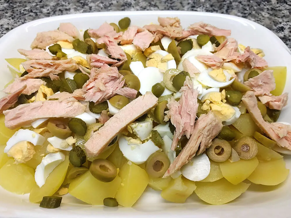 Patatas, huevos cocidos, pepinillos, olivas cortadas y bonito en aceite