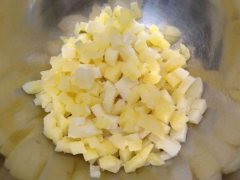 Patata cocida y cortada a dados en cuenco.