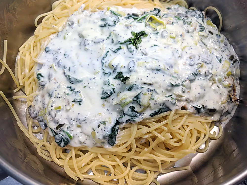 Espaguetis hervidos mezclados con la salsa de puerro, espinacas baby y crema de leche.