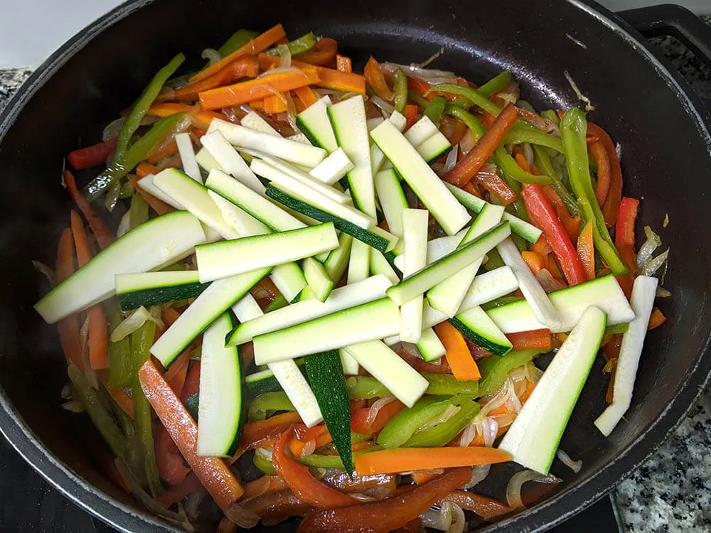 Pimientos verde y rojo, zanahoria, cebolla y calabacín en sartén.