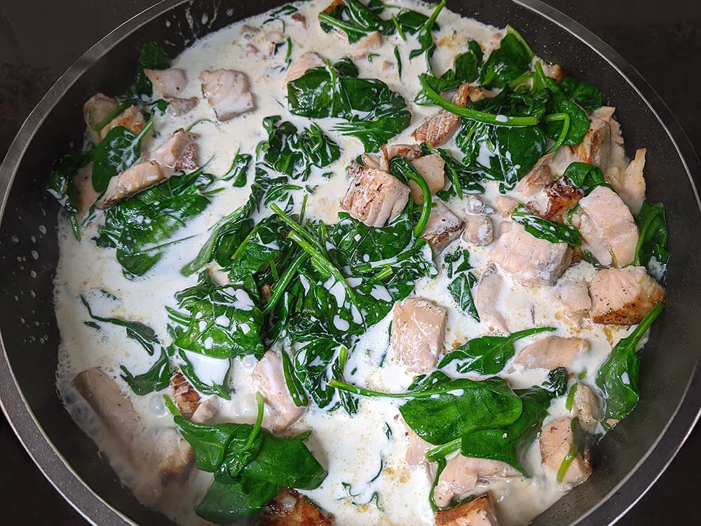 Dados de salmón, espinacas baby y nata de cocinar.