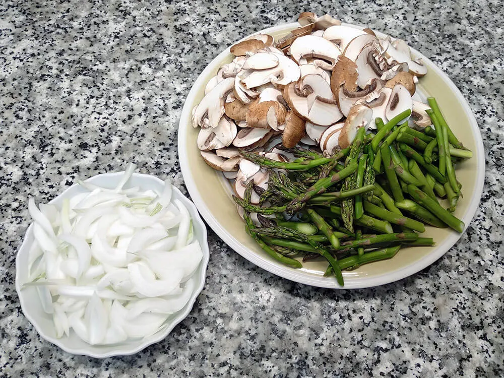 Cebolla, champiñones y espárragos cortados.