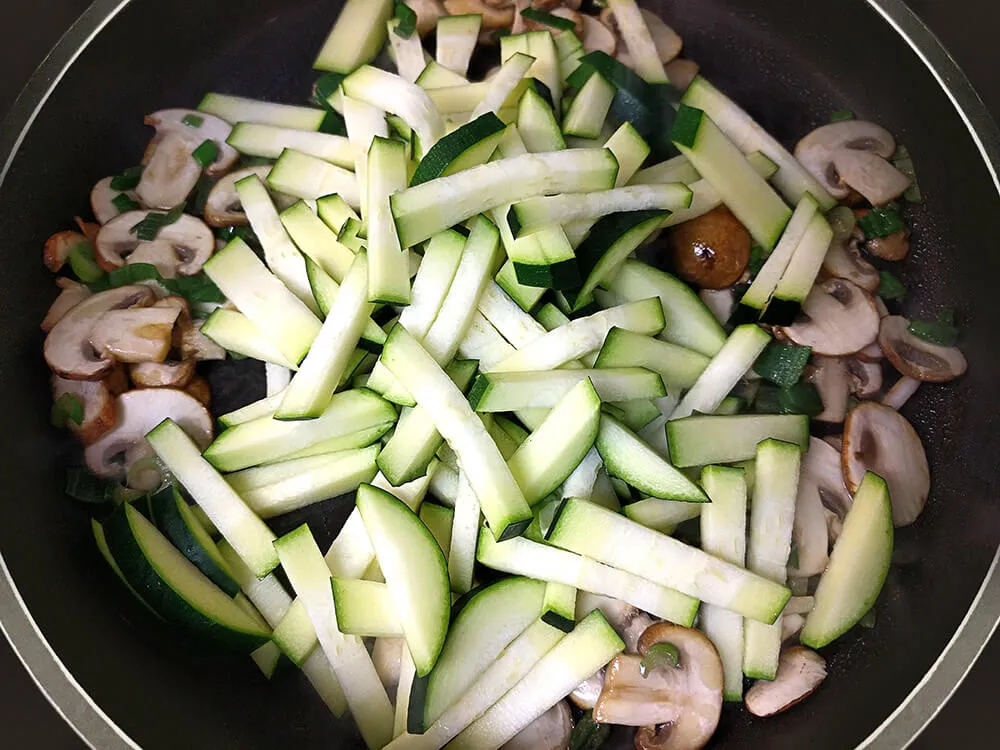 Champiñones, tallo de cebolleta y lacabacín rehogándose