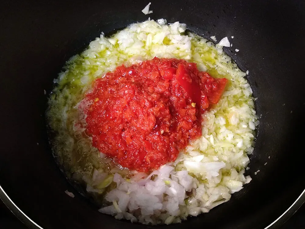 Cebolla, diente de ajo y pimientos picados en sartén con aceite de oliva.