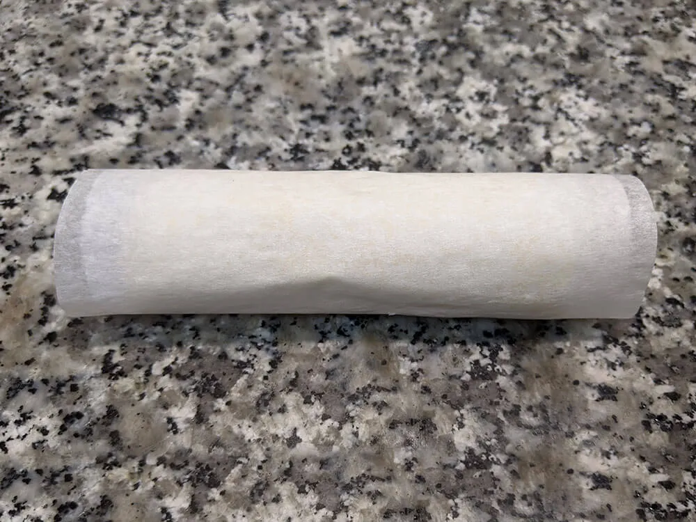 Rollo de hojaldre envuelto en papel de hornear.
