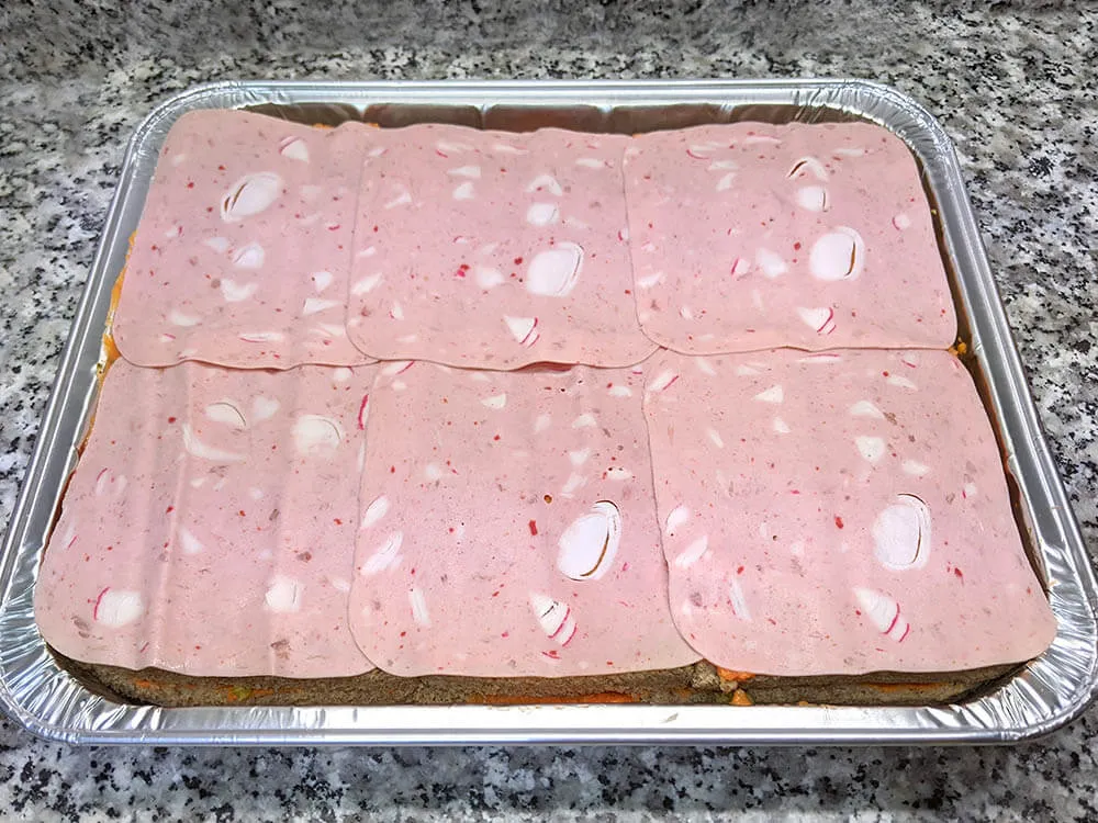 Capa de pan de molde untado con tomate triturado y Delisandwich de cangrejo.