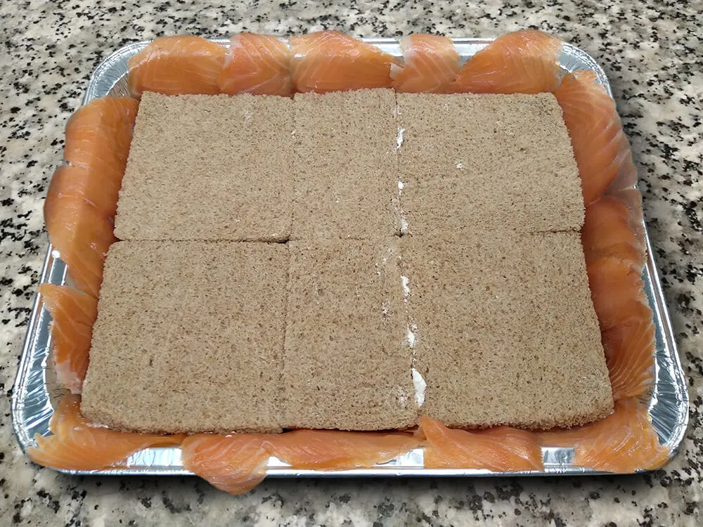Rebanadas de pan de molde untadas con queso crema por una banda.