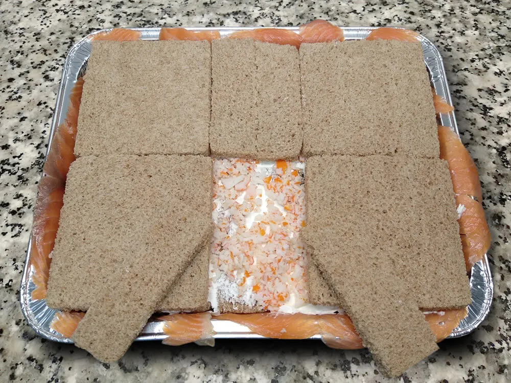 Rebanadas de pan de molde untadas con queso crema y surimi picado.