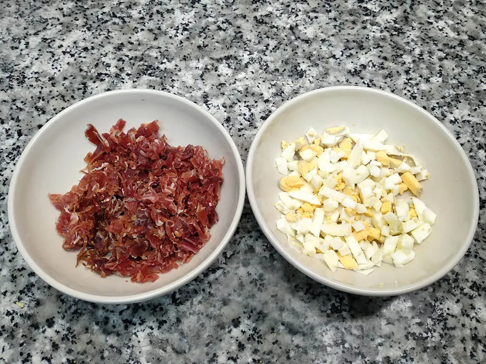 Huevo cocido picado y virutas de jamón ibérico.