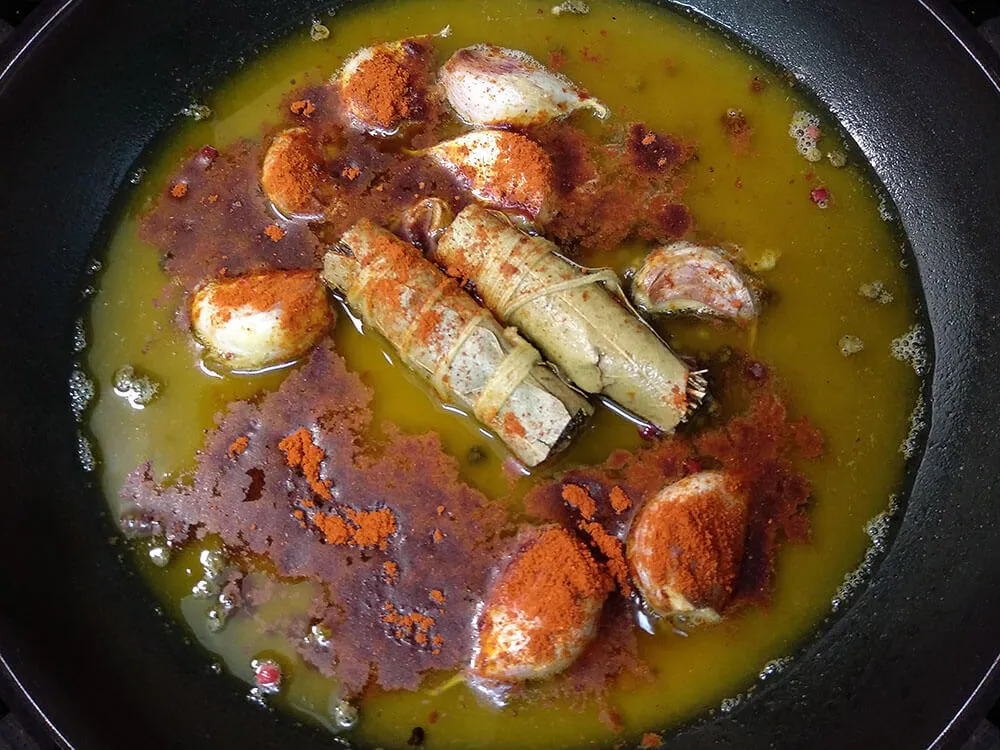 Sartén con aceite de oliva, pimienta, dientes de ajo, laurel, tomillo y pimentón.