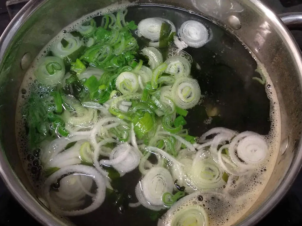Base de caldo de bonito con alga wakame y cebolla tierna.