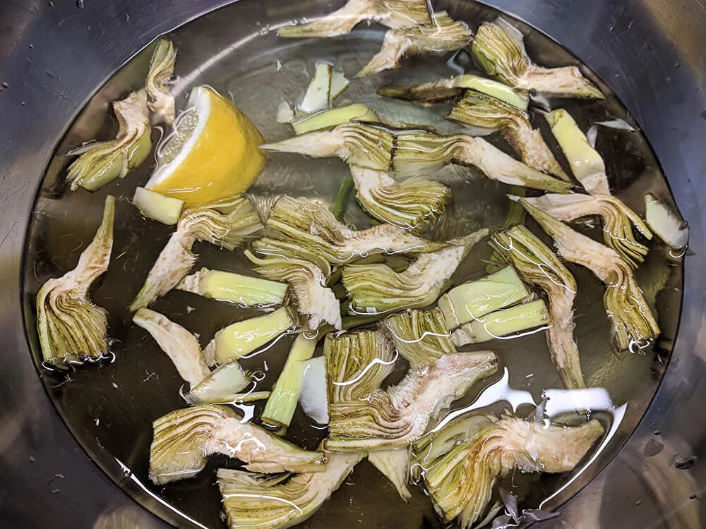 Alcachofas cortadas en remojo con agua y limón.