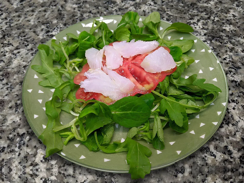 Canónigos, ruca, rodajas de tomate y bacalao.