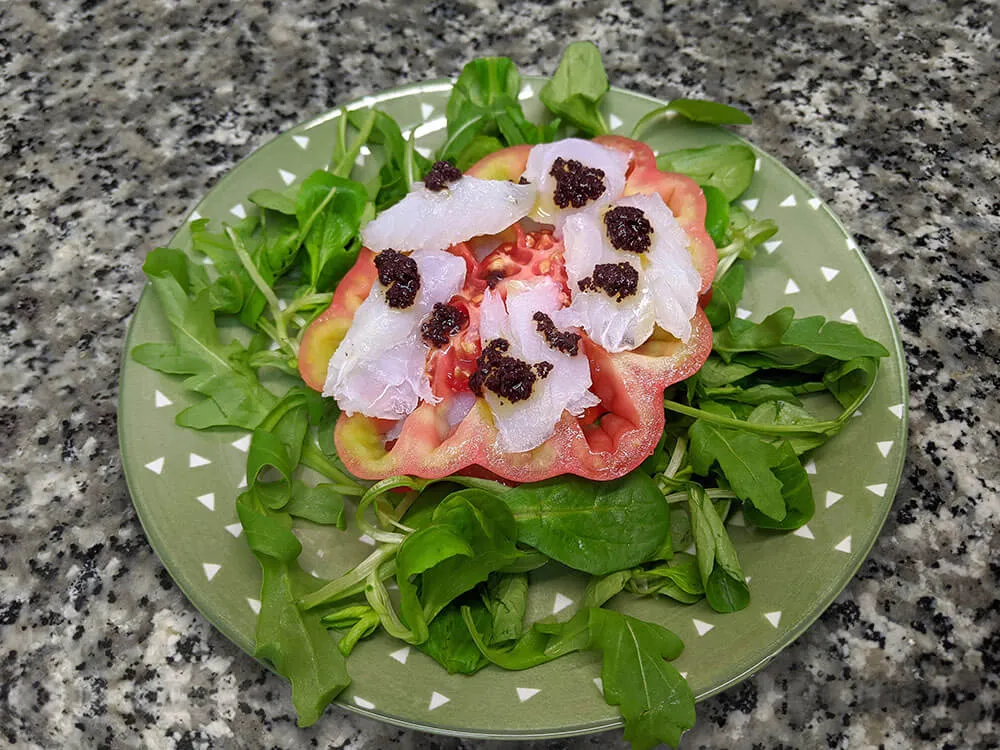 Canónigos, ruca, rodajas de tomate, bacalao y aliño de olivada.