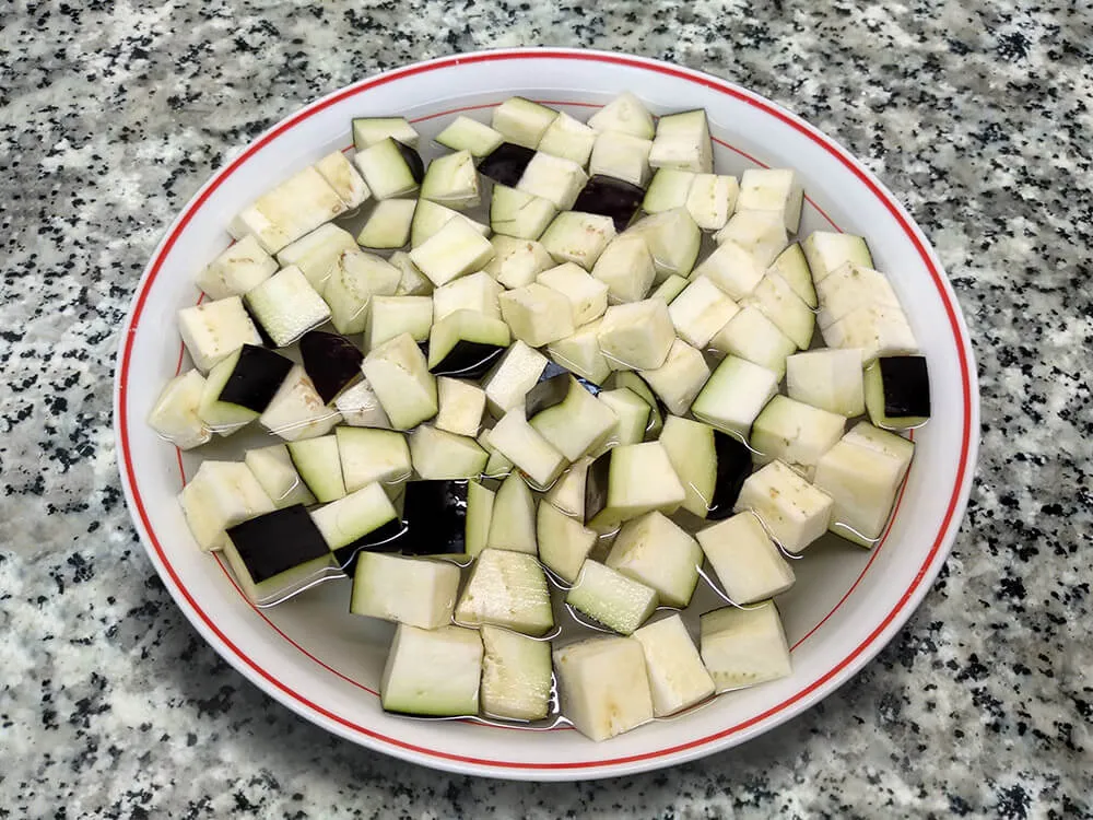 Berenjena cortada a dados en remojo.
