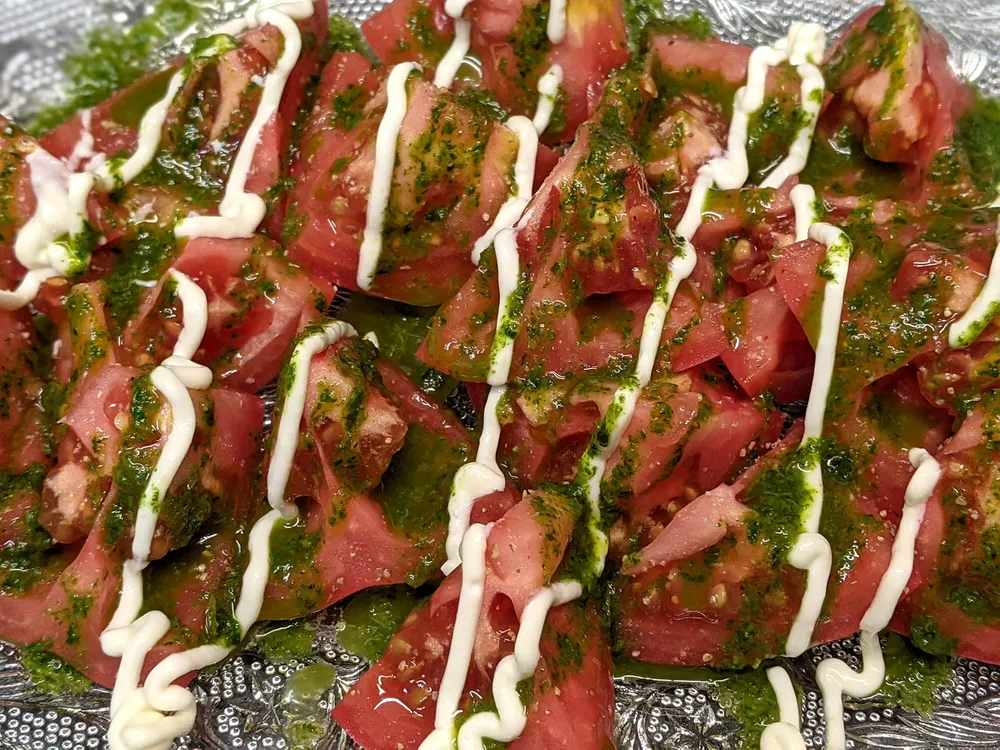 Ensalada de tomate Monterosa con aceite de albahaca y mayonesa de ajo.