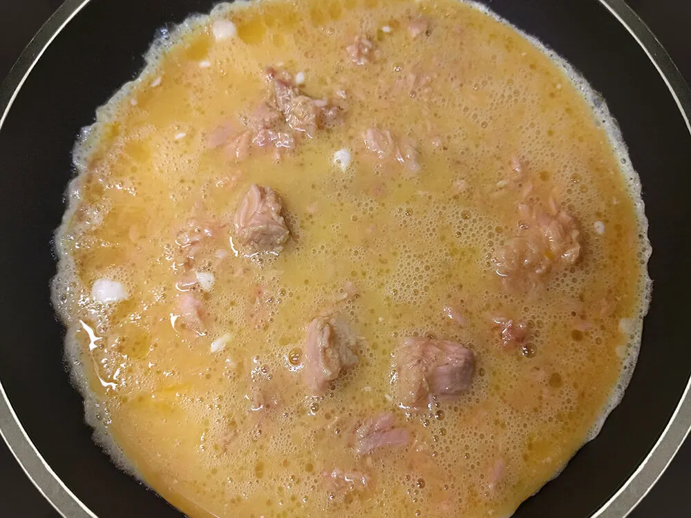 Huevos con atún cuajándose en la sartén