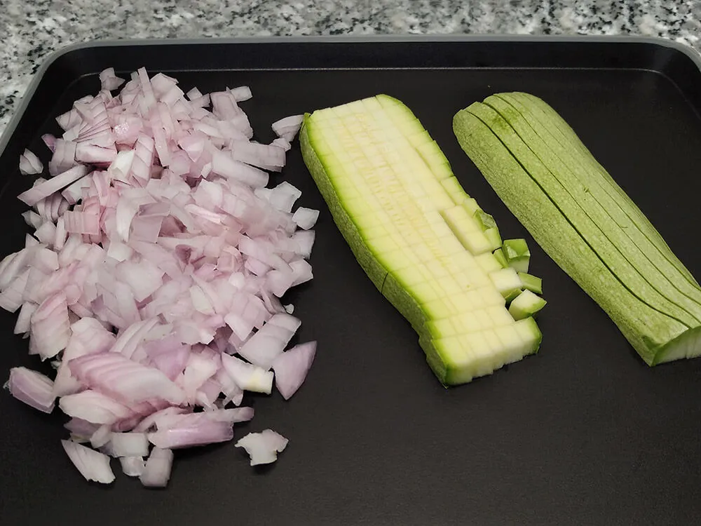 Calabacín y cebolla cortados a dados.