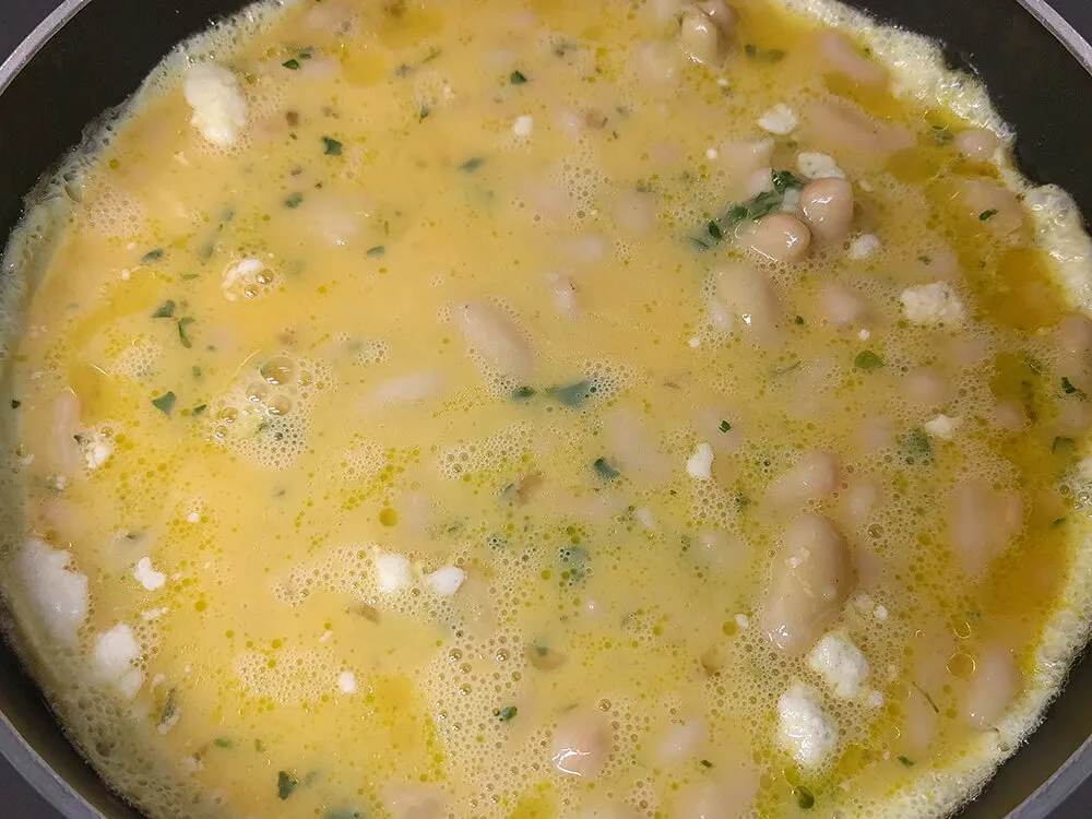 Huevos batidos con judías cuajándose en la sartén